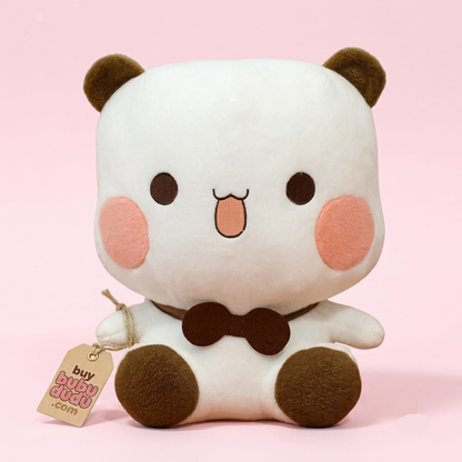 A cute white plush panda toy with brown ears, feet, and bow tie, pink cheeks, and a small stitched tongue sticking out. It is sitting against a solid light pink background and has a paper tag attached that reads 'buy BUBY BUBY.